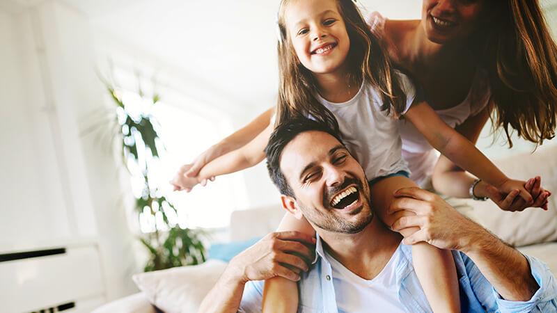 Father with daughter on shoulders and mother behind