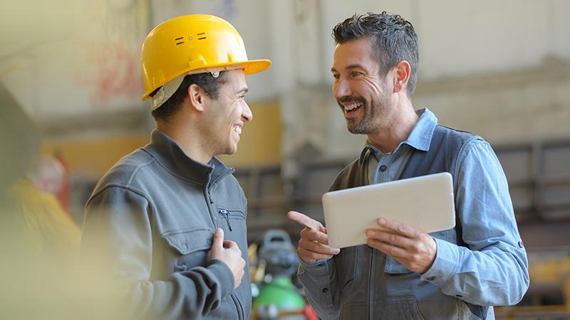 Two people at work, one has a hard hat