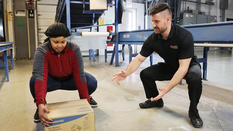 ATI demonstrating proper form to employee lifting a box